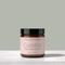 A jar of TALLOPHARM Cuddles Baby Bum Butter, featuring a black lid and a pale pink label, set on a light gray marble surface against a solid sage green background.
