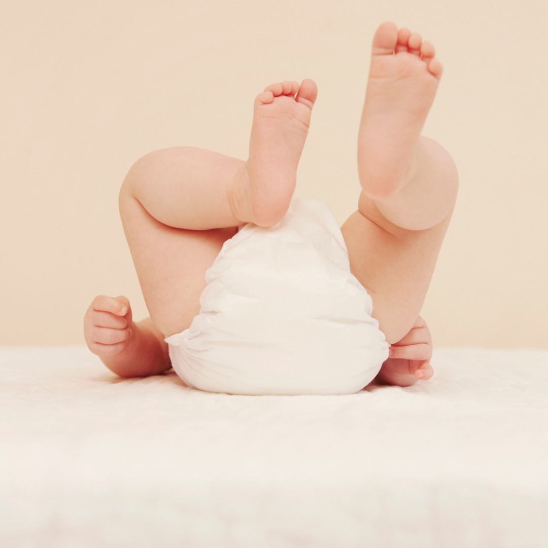 Baby legs with a diaper on a light beige background