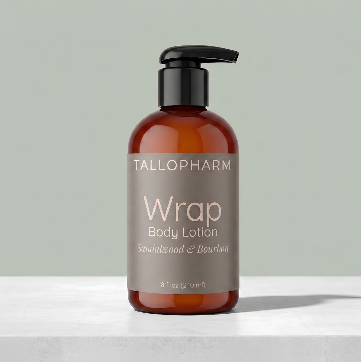 A bottle of Tallopharm Wrap Body Lotion with a black pump dispenser and a brown label, set on a white marble surface against a muted sage green background. Sandalwood and Bourbon fragrance.