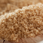 Close-up of brown sugar crystals held by a hand