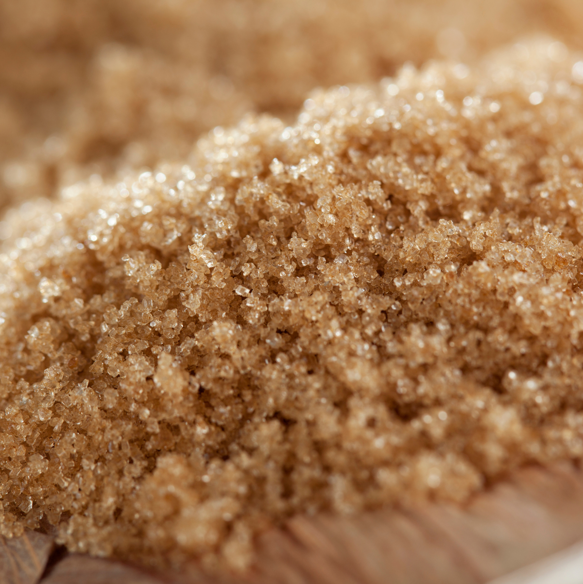 Close-up of brown sugar crystals held by a hand