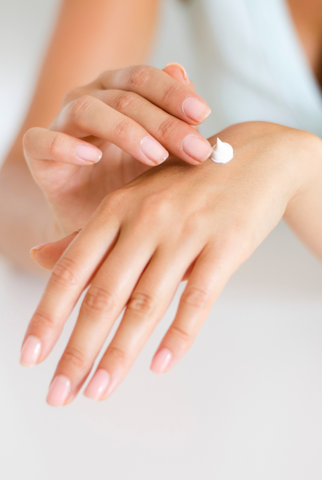 Hand showing a dollop of cream on a light background