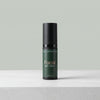 A bottle of Tallopharm Focal Eye Cream in a dark green bottle with a black cap, standing on a light gray textured surface against a solid sage green background.
