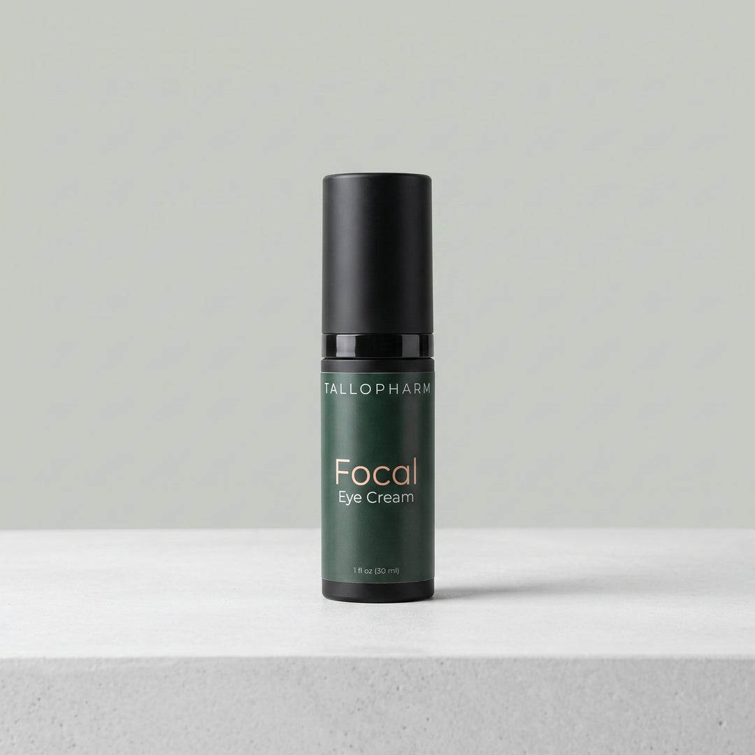 A bottle of Tallopharm Focal Eye Cream in a dark green bottle with a black cap, standing on a light gray textured surface against a solid sage green background.