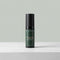 A bottle of Tallopharm Focal Eye Cream in a dark green bottle with a black cap, standing on a light gray textured surface against a solid sage green background.