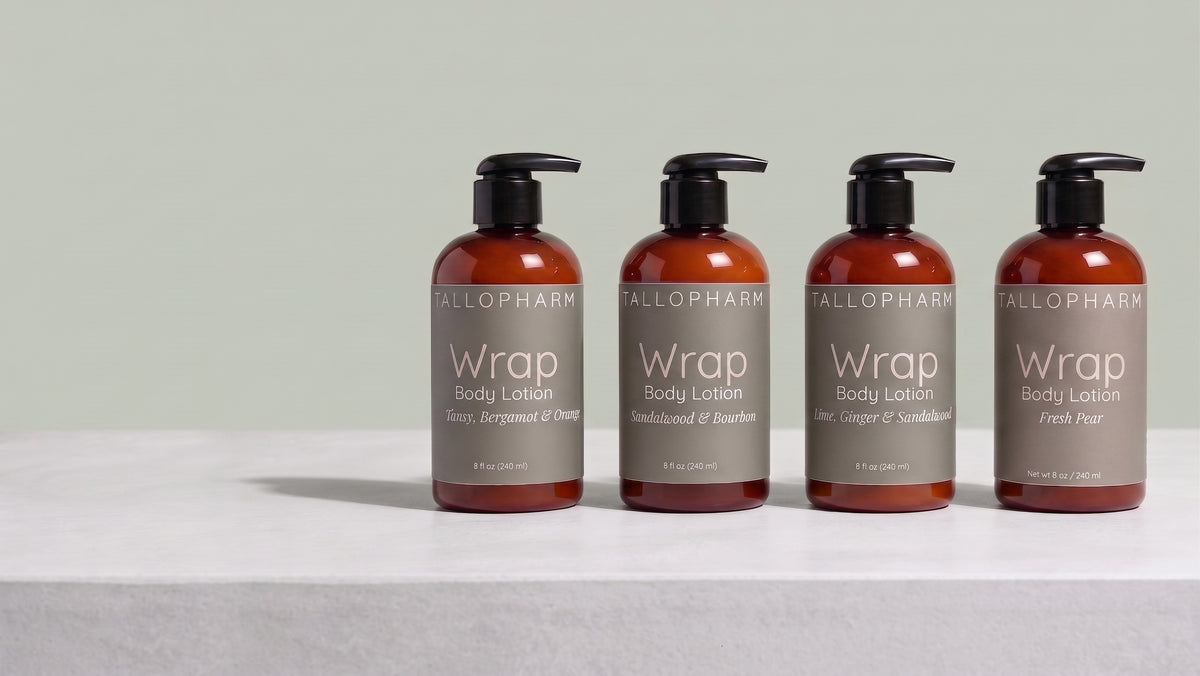 Four amber pump bottles of Tallopharm Wrap Body Lotion are arranged in a row on a light gray surface against a pale green background.