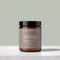 A jar of Tallopharm Wrap Body Butter in Fresh Pear, featuring an amber glass jar, a black lid, and a taupe label, set on a light gray marble surface against a sage green background.
