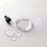 Glass dropper with clear liquid on a light gray background