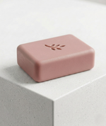 Pink soap bar with a leaf design on a light gray surface