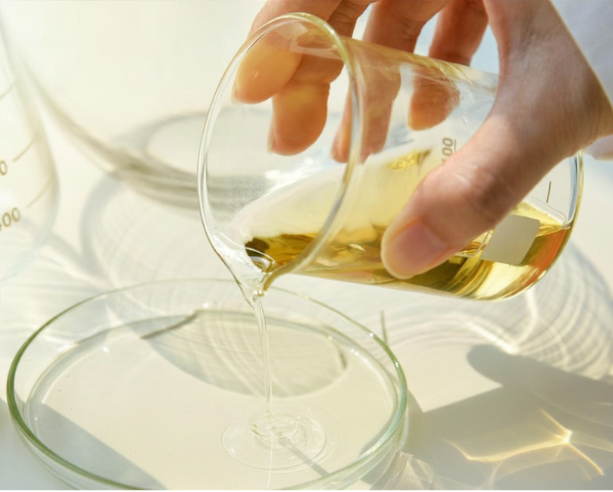 Hand holding and pouring a glass of oil with a blurred background