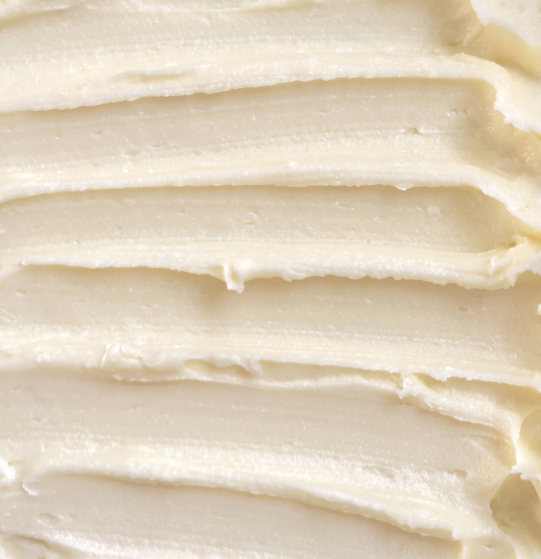 A close-up texture shot of thick, creamy off-white rich cream with horizontal ridges.