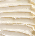 A close-up texture shot of thick, creamy off-white rich cream with horizontal ridges.