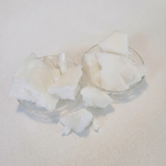 White solid beef tallow chunks displayed in two small clear glass bowls on a light beige textured surface.