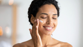 Smiling lady putting tallow face cream on her cheek.