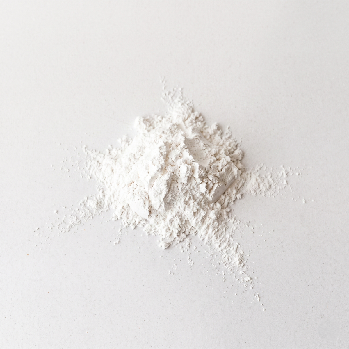 White non-nano zinc oxide powder on a light gray background